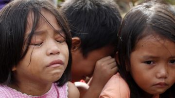 Un grupo de niños lloraba, ayer, tras escapar de su pueblo debido al caos que impera en regiones devastadas por el tifón.