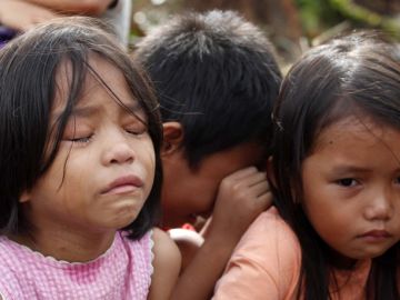 Un grupo de niños lloraba, ayer, tras escapar de su pueblo debido al caos que impera en regiones devastadas por el tifón.