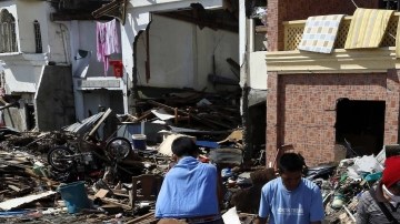 Tres hombres caminan entre los escombros tras el paso del devastador tifón Haiyan, en Tacloban (Filipinas), ayer.