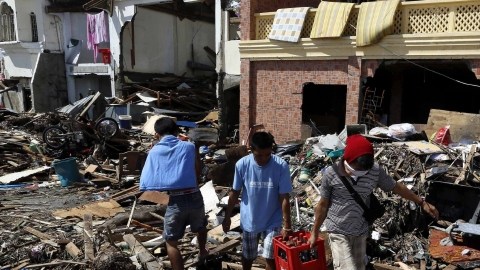 Tres hombres caminan entre los escombros tras el paso del devastador tifón Haiyan, en Tacloban (Filipinas), ayer.