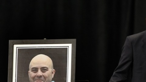 El fiscal general de Estados Unidos Eric Holder junto a un retrato del fallecido agente de la Administración de Seguridad en Transporte (TSA) Gerardo Hernández,en el homenaje realizado el 12 de noviembre de 2013, en Los Ángeles.
