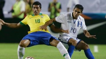 El brasileño Paulinho y el hondureño Jorge Claros disputan el esférico