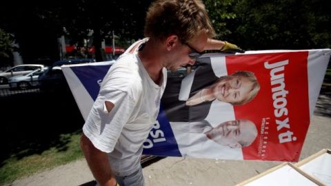 Un hombre retira un anuncio electoral el sábado previo a las elecciones presidenciales en Chile.