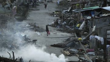 Víctimas del tifón en Filipinas caminan entre los escombros de la localidad de Basey, en la provincia de la Isla Samar. La búsqueda de los desaparecidos, 1,179 según el recuento oficial, es una situación infernal para muchos en Filipinas.