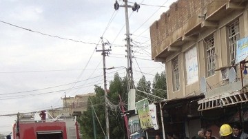 Ciudadanos observan trabajar a los bomberos en el lugar donde una bomba ha sido detonada en la ciudad de Najaf (Irak), ayer.