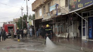 Ciudadanos observan trabajar a los bomberos en el lugar donde una bomba ha sido detonada en la ciudad de Najaf (Irak), ayer.