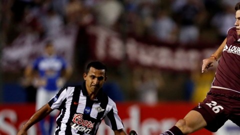El jugador del Libertad, Sergio Aquino (izq.), rechaza el disparo del delantero del Lanús, Lucas Melano.