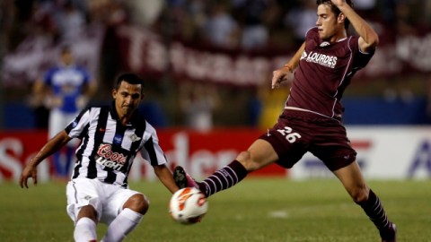 El jugador del Libertad, Sergio Aquino (izq.), rechaza el disparo del delantero del Lanús, Lucas Melano.