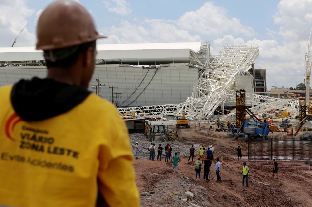 Varios trabajadores observan la estructura que colapsó en el Estadio Itaquerao en Sao Paulo.