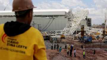 Varios trabajadores observan la estructura que colapsó en el Estadio Itaquerao en Sao Paulo.