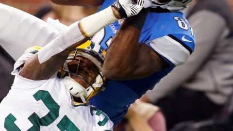 El ala receptor de Detroit, Calvin Johnson (81), alcanza a atrapar el ovoide ante el intento de Sam Shields (37) de arrebatárselo.