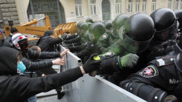 Manifestantes se resisten a la policía y tratan de pasar por encima de una barrera cerca del palacio presidencial, pidiendo la renuncia del Gobierno, ayer, en Kiev, Ucrania.