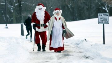 Will Mielenz y Beth Fandel, disfrazados como Santa Claus y la señora Claus, caminan junto al Lago Harriett, en Minneapolis, Minnesota.