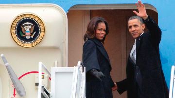 Barack Obama y su esposa Michelle abordaron el avión presidencial bajo un cielo lluvioso y frío para el largo viaje.