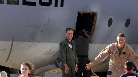 Niños scorren hacia un C-130 a recibir asus papás, marines de EEUU que regresan a casa después de cumplir misiones en el ultramar.
