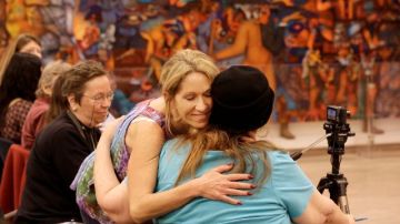Kristen D'Angelo, de frente, abraza a Carol Leigh en una reunión para pedir que cese la discriminación a los trabajadores del sexo al negarles beneficios luego de ser v'ictimas de crímenes violentos.