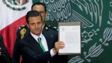 El presidente de México, Enrique Peña Nieto muestra los documentos que firmó que promulgan las reforma energética en el Palacio Nacional en la Ciudad de México, el viernes, 20 de diciembre 2013.