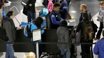 Una agente de seguridad del transporte (c) revisa el boleto de avión de un pasajero en la Terminal 3 del aeropuerto internacional O'Hare, en Chicago.