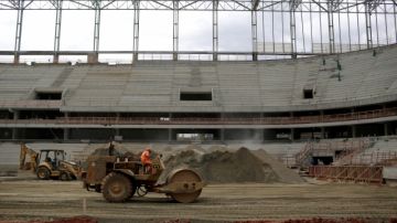 Trabajadores en  el Estadio  Baixada  de  Curitiba preparan el terreno para sembrar el césped que demarcará la cancha de juego.