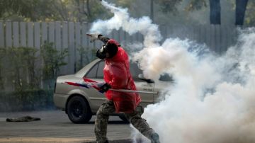 Un manifestante antigubernamental tailandés lanza una bomba de gas a la policía en un violento y mortal enfrentamiento de varias horas ayer frente a un estadio deportivo de Bangkok.