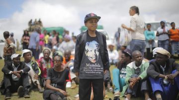 Un niño y cientos de personas observan el funeral de Nelson Mandela en una exhibición pública en su villa de Qunu, Sudáfrica.