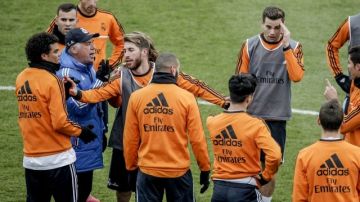 El técnico del Real Madrid, Carlo Ancelotti, rodeado de jugadores durante el último entrenamiento de 2013 del equipo celebrado hoy al calor de sus aficionados en el estadio Alfredo Di Stéfano que registró un lleno en sus gradas