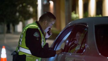 Un agente de la Policía de Los Ángeles detiene a un auto en un retén en busca de conductores ebrios.