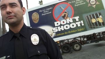 Un agente de la Policía se para frente a un anuncio que pide a las personas no disparar al aire para  festejar el Año Nuevo.