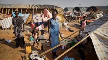 Una familia sursudanesa al lado de una tienda de campaña, que usan como refugio, en un campamento de las Naciones Unidas.