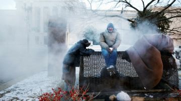 Cuatro personas sin hogar buscaban calentarse ayer cerca a una rejilla de vapor en Washington, D.C.