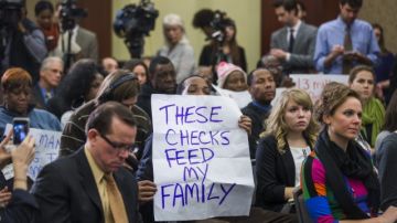 Varios asistentes a una rueda de prensa muestran pancartas en apoyo de la prórroga del subsidio de desempleo en EEUU.
