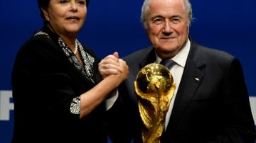 El presidente de FIFA, Joseph Blatter, posa con la presidenta de Brasil, Dilma Rousseff, mientras sostienen la Copa del Mundo.