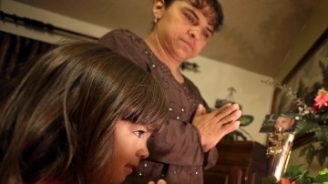 Irma Plascencia y su hija Mia, de 4 años, rezan junto al altar del padre, Israel Plascencia, en su casa de Pomona.