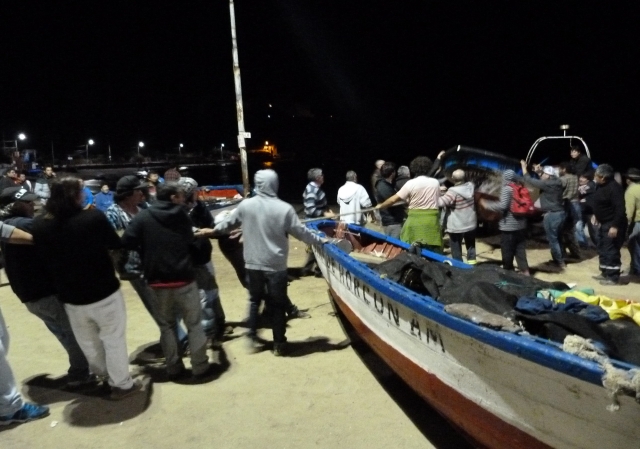 Un grupo de chilenos  saca sus botes de pesca del agua durante la alerta de 'tsunami' decretada con motivo del sismo.