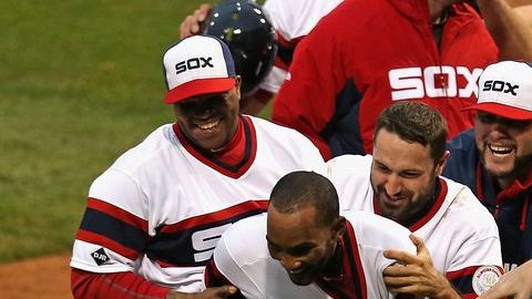 Alexei Ramirez de los Medias Blancas de Chicago es felicitado en home por sus compañeros tras pegar un tablazo impulsor de dos carreras en el cierre de la novena.