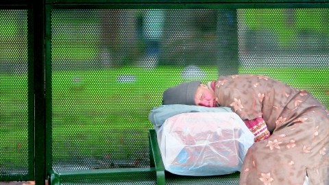 Una persona sin hogar duerme en una parada de buses del Parque MacArthur.