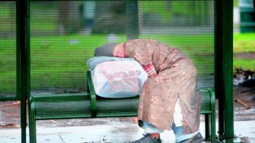 Una persona sin hogar duerme en una parada de buses del Parque MacArthur.