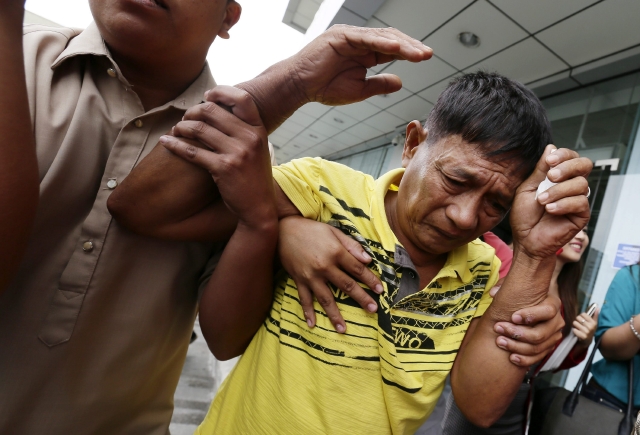 Un familiar de varias de las  víctimas de la tragedia del vuelo de Malaysia Airlines es escoltado antes de viajar a recuperar a sus familiares.