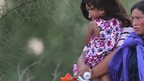 Migrantes centroamericanos esperan ser transportados a un centro de procesamiento tras cruzar el Río Bravo en Mission, Texas.