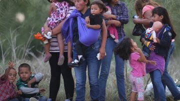 Migrantes centroamericanos esperan ser transportados a un centro de procesamiento tras cruzar el Río Bravo en Mission, Texas.