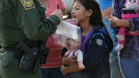 Un agente de la Patrulla Fronteriza atiende a una niña salvadoreña que le entrega documentos que la identifican, en Mission, Texas.