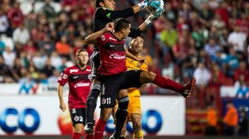 El arquero de Tigres,  Nahuel Guzmán, controla el balón ante  la mirada de uno de sus defensas y un delantero de Xolos