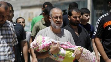 Un hombre carga a su nieta de 18 meses,  Zainah Abu-Taqeia, quien murió tras un ataque aéreo de Israel.
