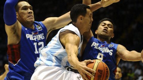 El base de la selección argentina Pablo Prigioni con el balón ante los jugadores de Filipinas June Mar Fajardo y Ranidel de Ocampo.