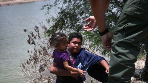 Un agente de la Patrulla Frontera ayuda a inmigrantes que cruzaron el Río Bravo, en Texas, el 24 de julio de 2014.