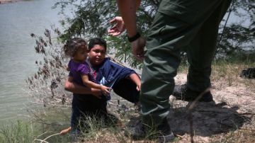 Un agente de la Patrulla Frontera ayuda a inmigrantes que cruzaron el Río Bravo, en Texas, el 24 de julio de 2014.