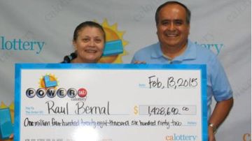 Raúl Bernal (der.), acompañado de su esposa, posa con el cheque de casi $1.5 millones que ganó en el sorteo.