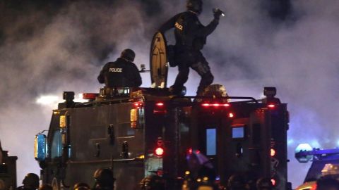 Un agente de Ferguson apunta a la multitud con botes de gas en agosto pasado.