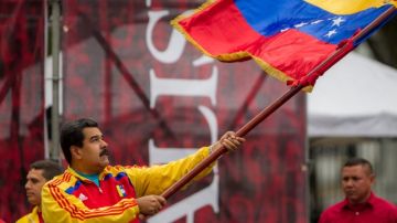 El presidente venezolano, Nicolás Maduro, ondea una bandera durante una concentración de manifestantes oficialistas ayer  en Caracas.