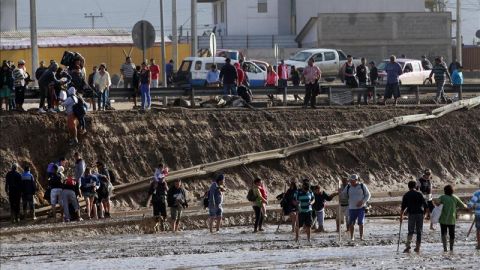 Personas afectadas cruzan el caudal del río formado tras las inundaciones torrenciales en Chañaral, al norte de Chile.